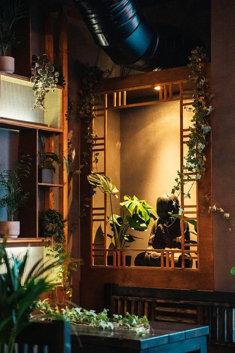 Buddha-Figur hinter Efeu und Monstera im House of Vegan